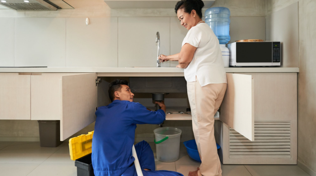 Technician conducting a pest inspection under a kitchen sink in Singapore